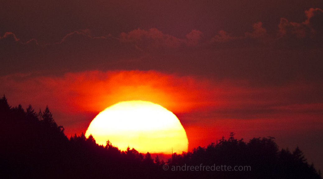 The sun, cradled by two hills on North Pender Island. August 12, 2015. Photo by Andrée Fredette